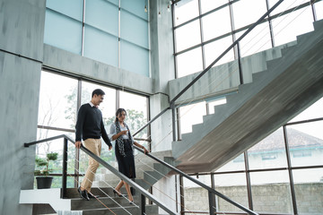 partner of business walking down with chatting on stairs in the office building