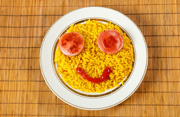 yellow rice on a plate with sausage in the form of eyes, fun food
