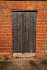 A wooden seasoned door in a brick out farm building