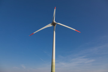 Fototapeta premium wind turbine with sun flare blue sky background view from below
