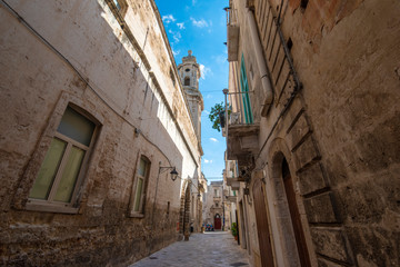 Street and alley with a view to the bell tower of Church of Saint Joseph and Anna  (Chiesa dei Santi Giuseppe e Anna) in the old town of Monopoli, Puglia, Italy. A region of Apulia