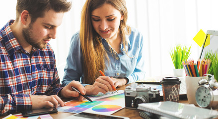 Obraz premium Two young creative designer colleagues using tablet at office