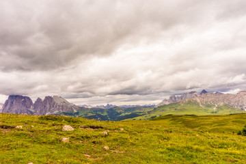 Fototapeta premium Alpe di Siusi, Seiser Alm with Sassolungo Langkofel Dolomite, a large green field with a mountain in the background