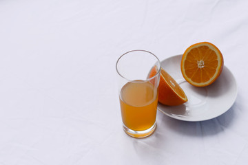 orange cut in half on a white plate on a white background and a glass of Fanta