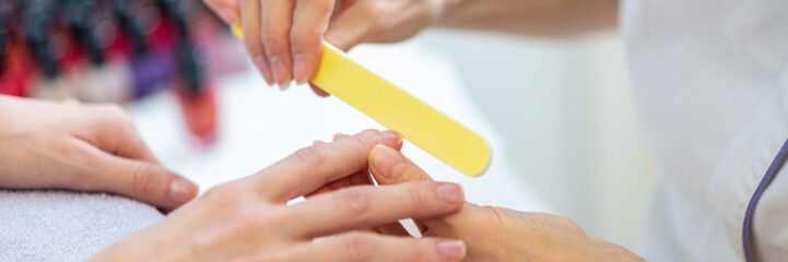 Manicurist using nail file to shape finger nails