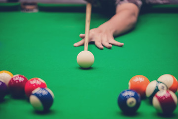 Male hand playing Snooker or Pool game on green table.