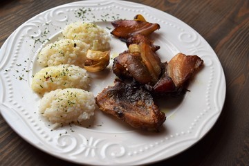 Roasted pork meat in bacon with rice on a white plate