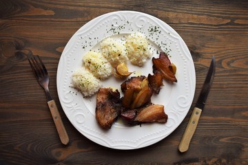 Roasted pork meat in bacon with rice on a white plate