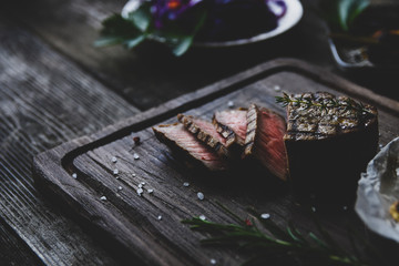 Fleisch Steak auf einem Alte Schneidbrett mit dunkel hintergrund Salz und Kräuter