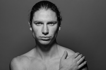 Portrait of a muscular long-haired man with drawn hair and freckles, topless