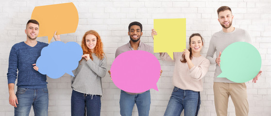 Friends holding empty speech bubbles over white wall