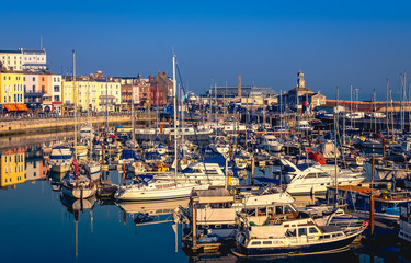 The impressive and historic Royal Harbour of Ramsgate, Kent, Uk, full of leisure and fishing boats of all sizes and the colourful facade of the historic buildings along the marina promenade and clock 