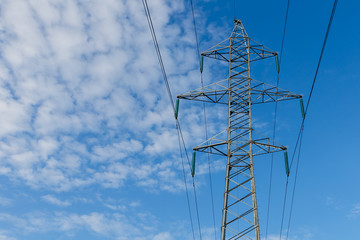 Power lines on metal pillars against a blue sky with clouds