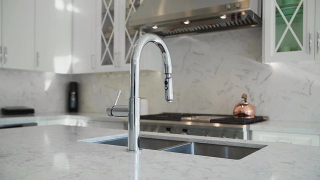 Stainless steel faucet in a modern marble kitchen.