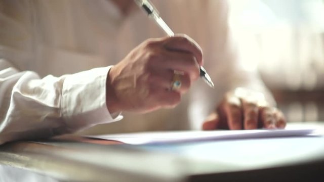 A male hand edits a printed document with a pen on a wooden table.