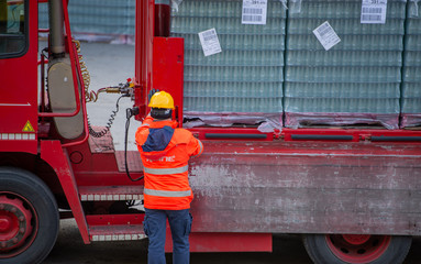 Truck driver secures the loading of bottles of mineral water by binding it with ropes before...