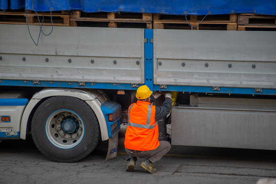 Truck driver secures the loading of bottles of mineral water by binding it with ropes before starting the transport