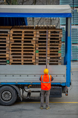 Truck driver secures the loading of bottles of mineral water by binding it with ropes before...