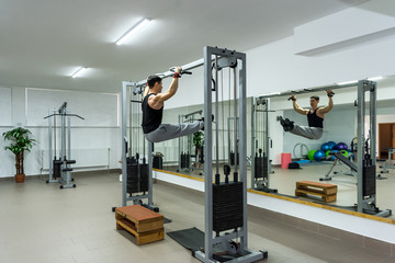 Fototapeta na wymiar Man in gym doing some exercises on crossbar