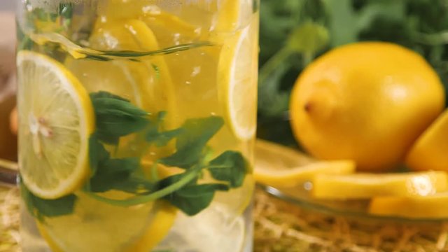 Stir tea in glass with spoon. Fresh hot tea with mint and lime inside.