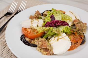 White cheese salad with tomato, eggplant and cabbage on a plate.