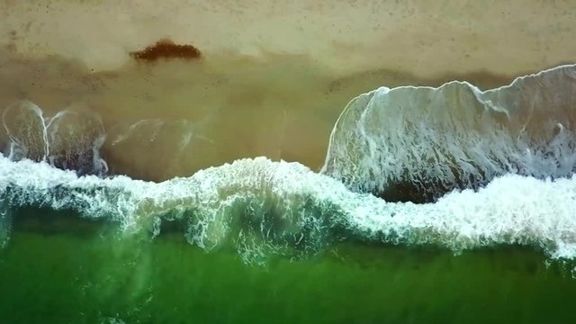 Seeing downwards waves hitting the beach in Prora, Germany as you pan along the shore