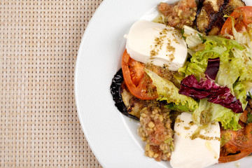 White cheese salad with tomato, eggplant and cabbage on a plate.