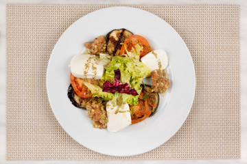 White cheese salad with tomato, eggplant and cabbage on a plate.