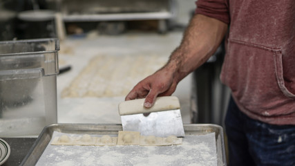 Chef hands preparing fresh Italian Ravioli pasta in an industrial kitchen