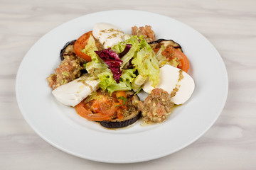 White cheese salad with tomato, eggplant and cabbage on a plate.