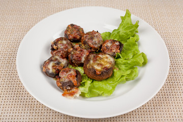 Baked champignon mushrooms stuffed with green salad on a white plate.