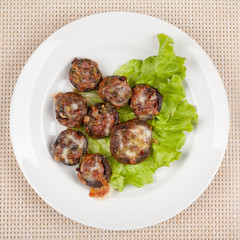 Baked champignon mushrooms stuffed with green salad on a white plate.