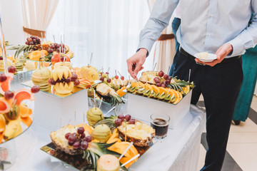 Man tasting assortment of exotic fruit at a wedding reception buffet table
