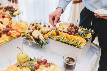 Man tasting assortment of exotic fruit at a wedding reception buffet table