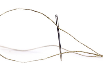 Coarse thread ball and needle on white background. Linen coarse gray threads and needle.