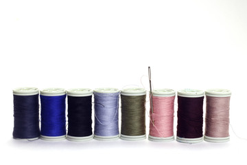  Different color spools of thread with needle.