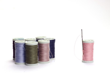  Different color spools of thread with needle.