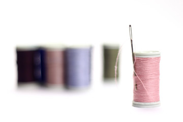 Different color spools of thread with needle.