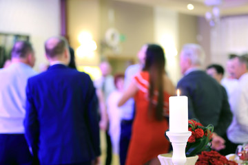 Fototapeta Biała świeca i ludzie w tańcu na przyjęciu weselnym. obraz