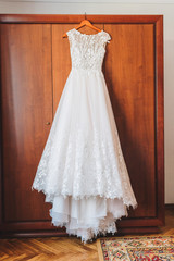 beautiful A-line wedding dress with floral embroidery is hanging in the morning of a wedding day