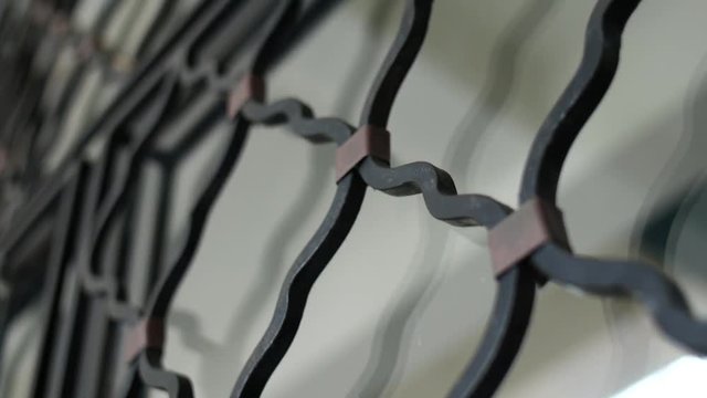 Close shot of an iron grille covering a window in slow motion.