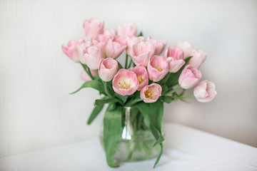 A bouquet of spring beautiful flowers in a glass vase. Fresh Pink tulips on white background.