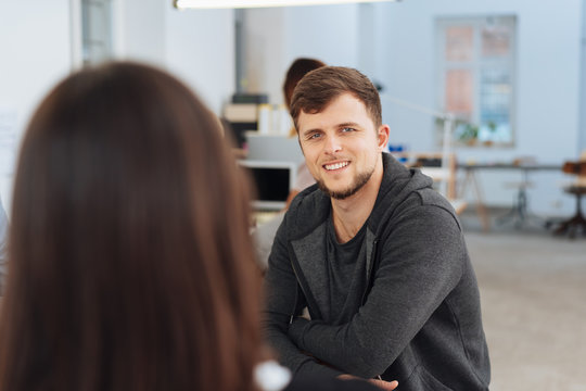 Smiling young businesswoman talking to a colleague