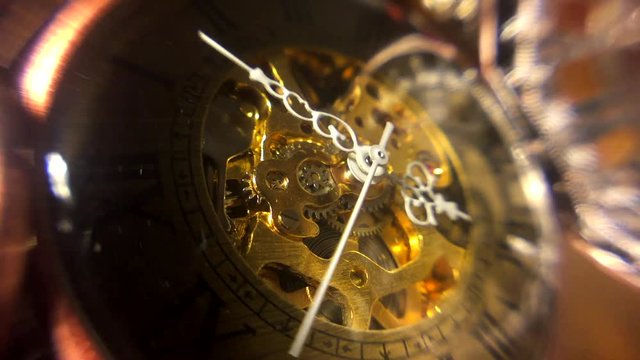 Vintage mechanical pocket watch. Macro close up of watch face and hands with soft edges and shadows. Hands moving and mechanical gears exposed.
