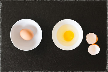 whole egg broken egg with egg shells in a bowl with black slate background