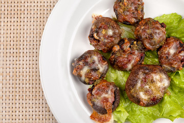 Baked champignon mushrooms stuffed with green salad on a white plate.