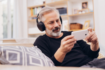 Older man relaxing listening to music on his phone