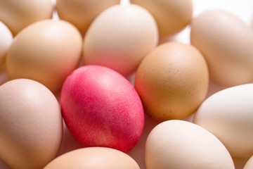 Easter red egg among brown and white eggs, top view