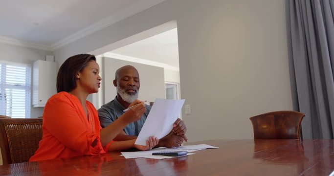 Front view of mature black couple discussing domestic bills in a comfortable home 4k