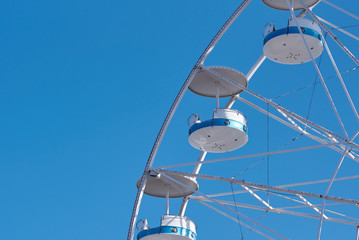 Part of panoramic wheel in amusement park against clear summer blue sky.